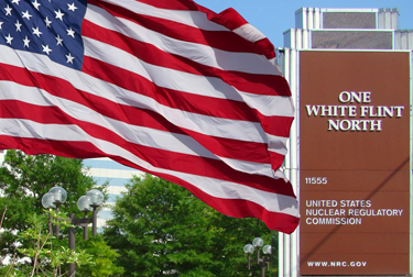 Image of the Nuclear Regulatory Commission's outdoor building signage at their headquarters in Maryland with an American Flag flying next to it.